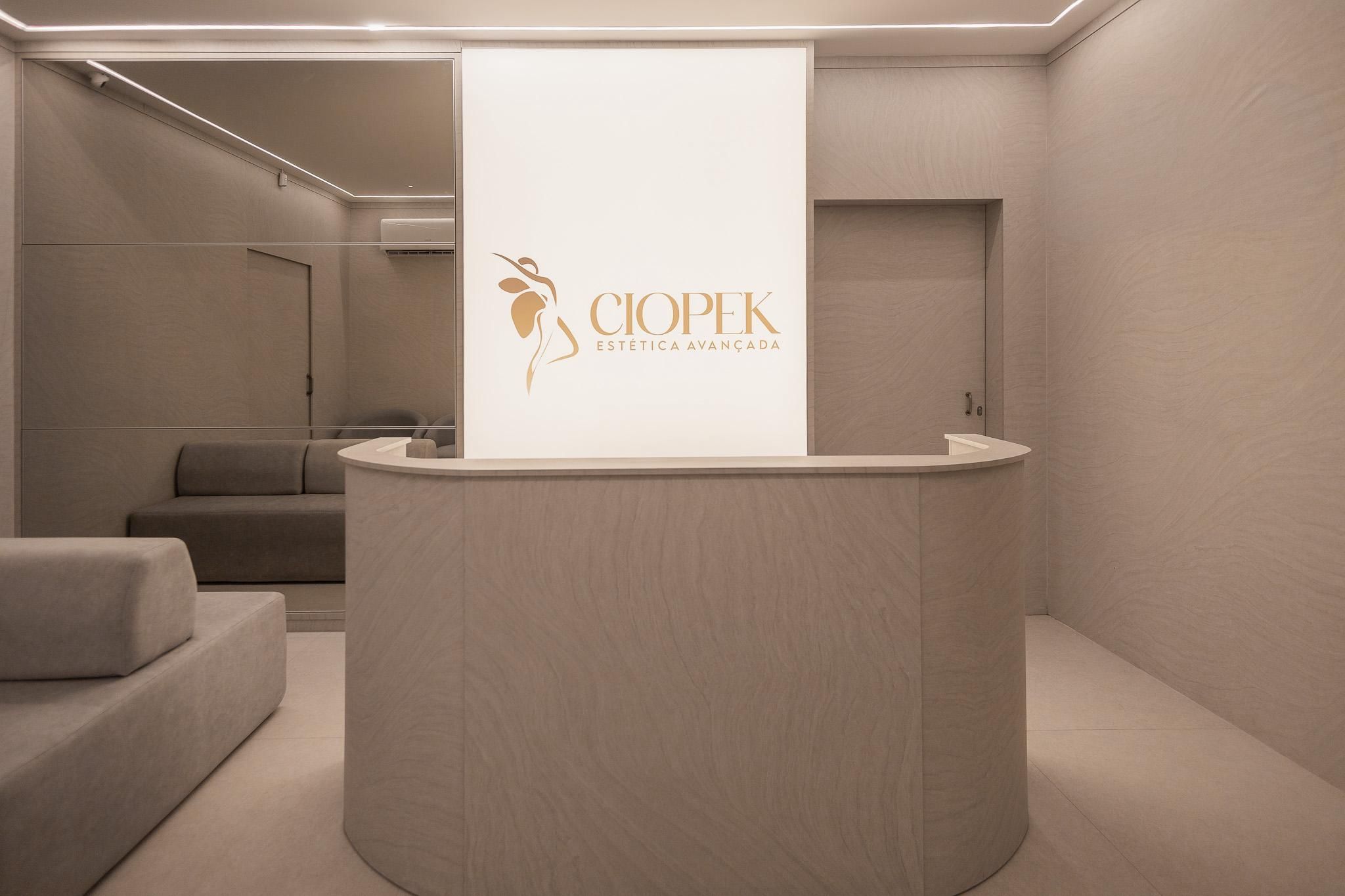 Sala de espera com sofás claros e o painel da marca